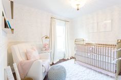 a baby's room with a white crib, pink and gold decor and a chandelier