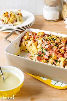 a casserole dish with ham and cheese in it on a table next to plates