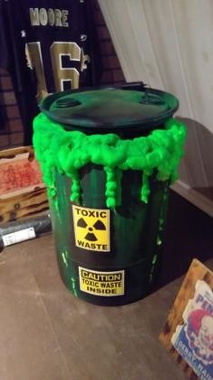 a green trash can sitting on top of a table next to a sign and other items