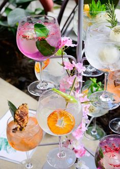 several glasses filled with different types of drinks and garnished with flowers on the table