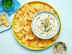 a bowl of dip and chips on a yellow plate next to a glass of water