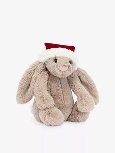 a stuffed rabbit wearing a santa hat on top of it's head, sitting in front of a white background