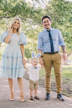 a man and woman holding hands while standing next to a small child wearing bunny ears