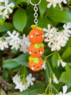 three carrots are hanging from a chain in front of some white flowers and green leaves