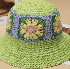 a green crocheted hat sitting on top of a table next to a book