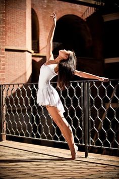 a woman in white dress standing on one leg with her arms up and legs spread out