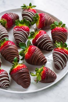 chocolate covered strawberries are arranged on a white platter, ready to be eaten