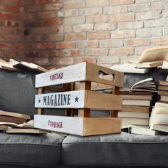 a stack of books sitting on top of a couch next to a pile of magazines