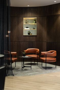 two chairs and a table in a room with dark wood paneling on the walls