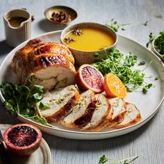 a white plate topped with sliced turkey next to oranges and garnishes