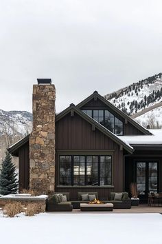 a house with snow on the ground and mountains in the background