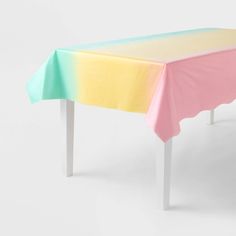 a table with a pink, yellow and green tablecloth on it's top