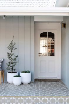 two white planters sitting in front of a door on the side of a house