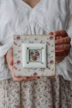 a woman holding a small white plate with a flowered design on the front and side