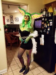 a woman with green hair and costume posing in front of a refrigerator