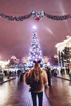 a woman standing in front of a christmas tree