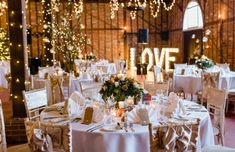 the tables are set with white linens and decorated with flowers, candles and greenery