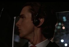 a man wearing headphones in the back seat of a car with city lights behind him