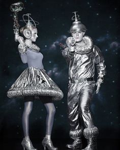 two people dressed in silver standing next to each other on a black and white background