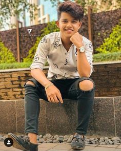 a young man sitting on top of a stone bench