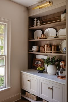 the shelves in this kitchen are filled with plates and bowls, vases and other items