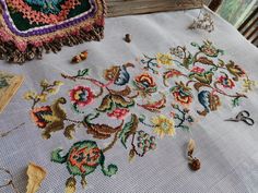 an embroidered table cloth with scissors and other items on it