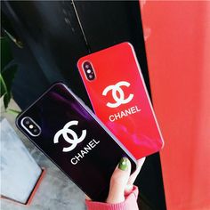 two chanel phone cases are being held up in front of a red and black wall