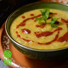 a bowl filled with soup and garnished with parsley on top, sitting on a plate