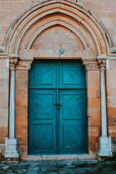 an old building with two blue doors and arches on the front door is shown in color