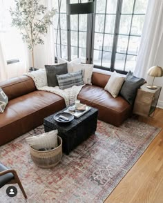 a living room with brown leather couches and pillows on top of a large rug