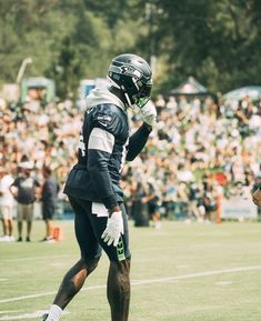 a football player is walking on the field with his hand in his pocket and people behind him