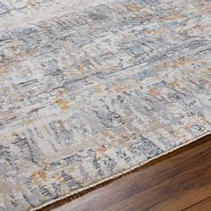 an area rug with wooden floors and wood flooring in the background, including a large gray