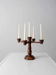 a wooden candelabra with five candles on it's side and white walls in the background