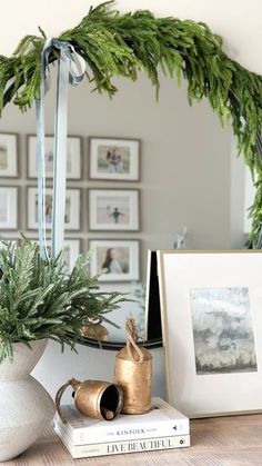 there is a mirror and some pictures on the table in front of it with plants