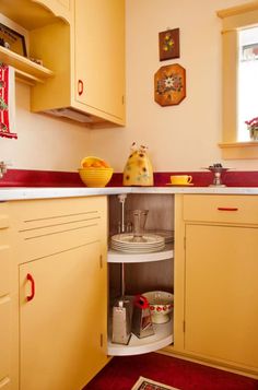 a kitchen with yellow cabinets and red counter tops, an area rug on the floor