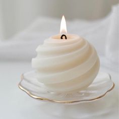 a white candle sitting on top of a glass plate