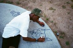 a man sitting on top of a cement slab drawing something with chalk and marker pens