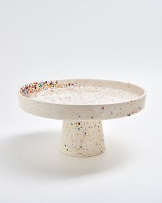 a white cake plate with sprinkles on the top and bottom, in front of a white background