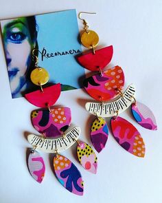 a pair of colorful earrings with music notes on them next to a card and photo