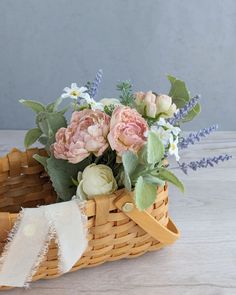 a basket filled with flowers sitting on top of a wooden table next to a white ribbon