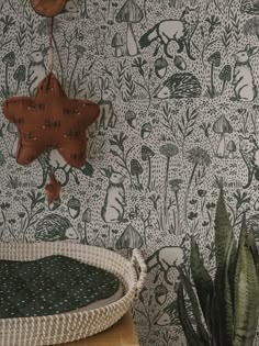 a room with a bed and wallpaper that has animals on it, including a star hanging from the ceiling