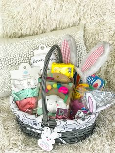 a basket filled with baby items sitting on top of a couch next to a pillow