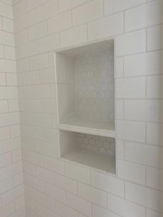 an empty white shelf in the corner of a room with tile on the walls and floor