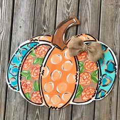 a painted pumpkin sitting on top of a wooden table next to a fence with a bow