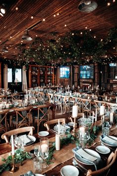 a large dining room set up for an event with candles and place settings on the tables