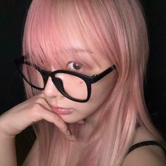 a woman with pink hair and black glasses