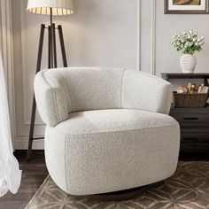 a white chair sitting on top of a wooden floor next to a lamp and table