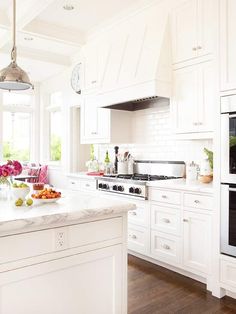 a kitchen with white cabinets and an island in front of the stove, oven and microwave