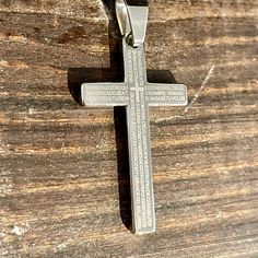 a silver cross on a wooden surface with the word jesus engraved in it's center