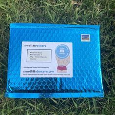 the small blue box is laying in the grass with it's label on it